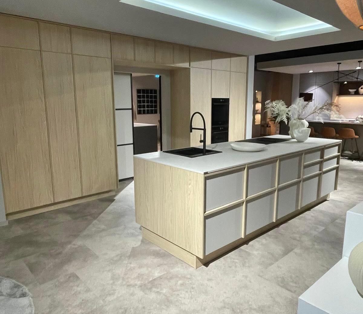 Cocina publicada por Arte Diseño Mobiliario, con frentes de madera clara e isla blanca